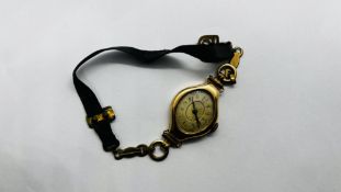 A VINTAGE LADIES WRIST WATCH ON MATERIAL STRAP CASE MARKED 14K.