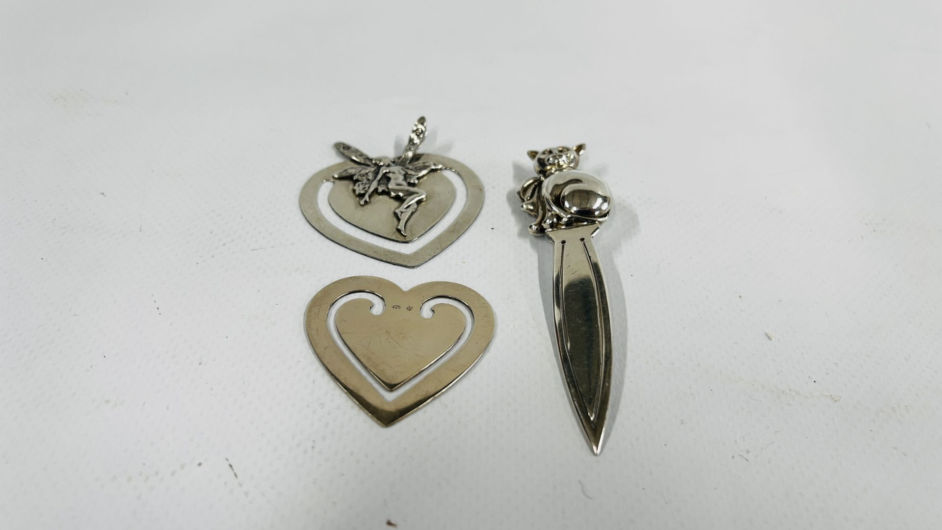 A GROUP OF THREE SILVER BOOKMARKS TO INCLUDE A FAIRY AND CAT EXAMPLES.