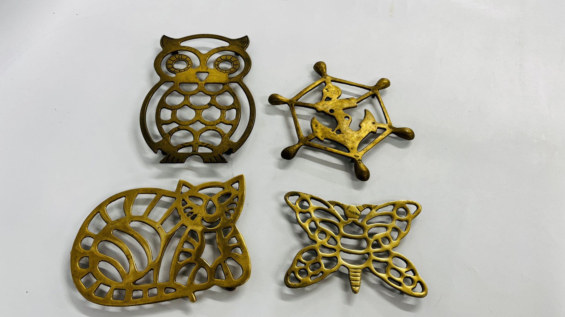 A GROUP OF 4 VINTAGE BRASS TRIVETS TO INCLUDE AN EXAMPLE IN THE FORM OF A CAT AND AN OWL ETC.