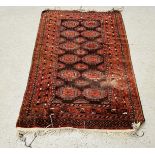 A RED PATTERNED EASTERN RUG 193CM X 125CM.