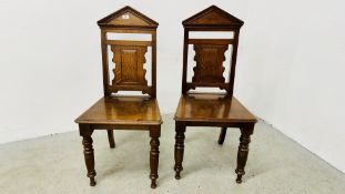 A PAIR OF SOLID OAK EDWARDIAN PANEL BACK HALL CHAIRS WITH PEDIMENTED BACKS A/F.