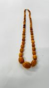 A STRAND OF AMBER TYPE BEADS.