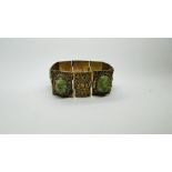 A VINTAGE GILT FILAGREE BRACELET, THE PANELS INSET WITH OVAL CARVED JADE STONES.