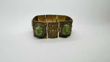 A VINTAGE GILT FILAGREE BRACELET, THE PANELS INSET WITH OVAL CARVED JADE STONES.