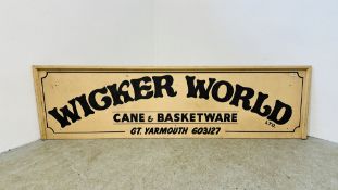 A WOODEN ADVERTISING SIGN "WICKER WORLD" - LENGTH 227CM HEIGHT 63CMM.