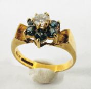 A CONTEMPORARY 9CT GOLD FLOWER HEAD RING SET WITH A CENTRAL DIAMOND SURROUNDED BY SMALLER GREEN