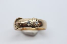 A 9CT GOLD BUCKLE RING SET WITH TWO DIAMONDS.