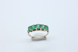 A 9CT GOLD 5 STONE EMERALD RING, THE SHOULDERS SET WITH 3 SMALL DIAMONDS EITHER SIDE.