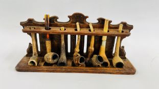 A VINTAGE OAK PIPE STAND RETAINING 7 VINTAGE PIPES TO INCLUDE CLAY EXAMPLES.