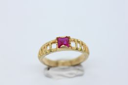 AN UNUSUAL DESIGNER RING WITH OPEN WORK SHOULDERS SET WITH A CENTRAL PINK SQUARE CUT STONE MARKED