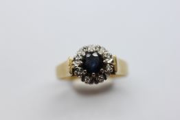 A DIAMOND AND SAPPHIRE CLUSTER RING MARKED 750.