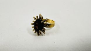 AN UNUSUAL 9CT GOLD DECO FLOWER HEAD STYLE RING SET WITH A CENTRAL RUBY RED COLOURED STONE.