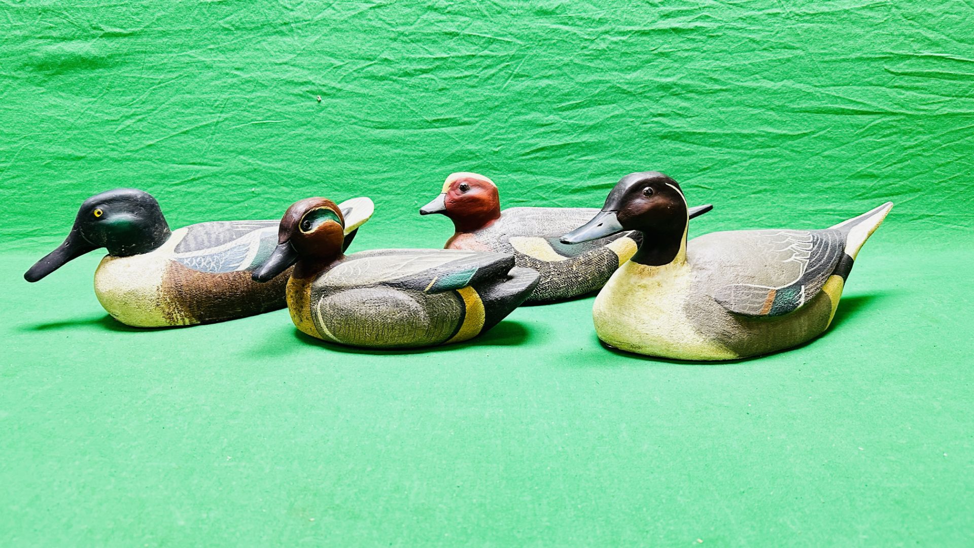 A HANDCRAFTED SET OF 4 DUCK DECOYS HAVING HANDPAINTED DETAIL AND GLASS EYES.