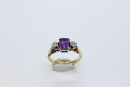 AN 18CT GOLD RING SET WITH A CENTRAL EMERALD CUT AMETHYST AND A DIAMOND EITHER SIDE.