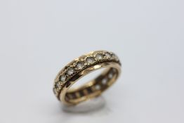 A 9CT GOLD ETERNITY RING SET WITH CLEAR STONES.
