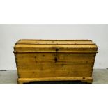 A VINTAGE WAXED PINE TWO HANDLED DOMED TOP TRUNK WITH ORIGINAL KEY - W 119CM X D 55CM X H 72CM.