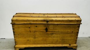 A VINTAGE WAXED PINE TWO HANDLED DOMED TOP TRUNK WITH ORIGINAL KEY - W 119CM X D 55CM X H 72CM.