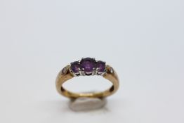 A 9CT GOLD 3 STONE AMETHYST RING INSET WITH A SMALLER DIAMOND TO EITHER SHOULDER.