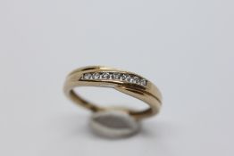 A 9CT GOLD RING SET WITH A ROW OF 7 CHANNEL SET DIAMONDS.