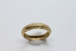 A 9CT GOLD WEDDING BAND, WITH A PATTERNED FINISH.