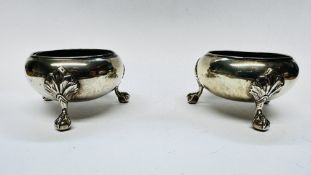 A PAIR OF VICTORIAN SILVER SALTS ON THREE RAISED BALL AND CLAW FEET, WITH BLUE GLASS LINERS,