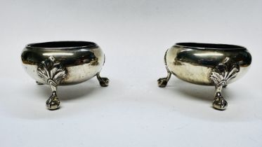 A PAIR OF VICTORIAN SILVER SALTS ON THREE RAISED BALL AND CLAW FEET, WITH BLUE GLASS LINERS,