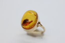 A 9CT GOLD RING SET WITH AN OVAL AMBER TYPE STONE.