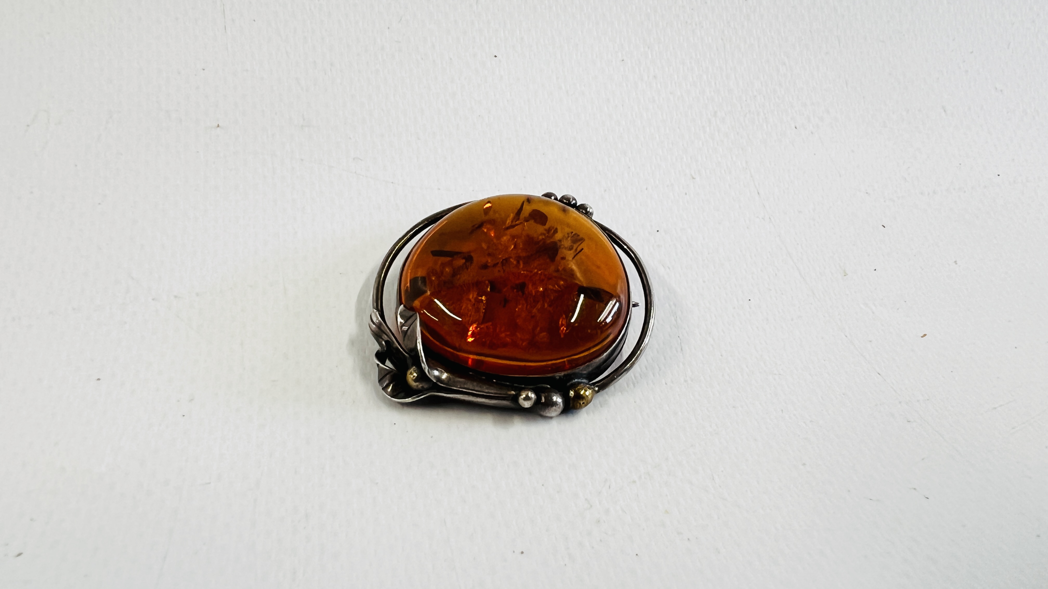 A VINTAGE SILVER BROOCH INSET WITH AN AMBER TYPE STONE.