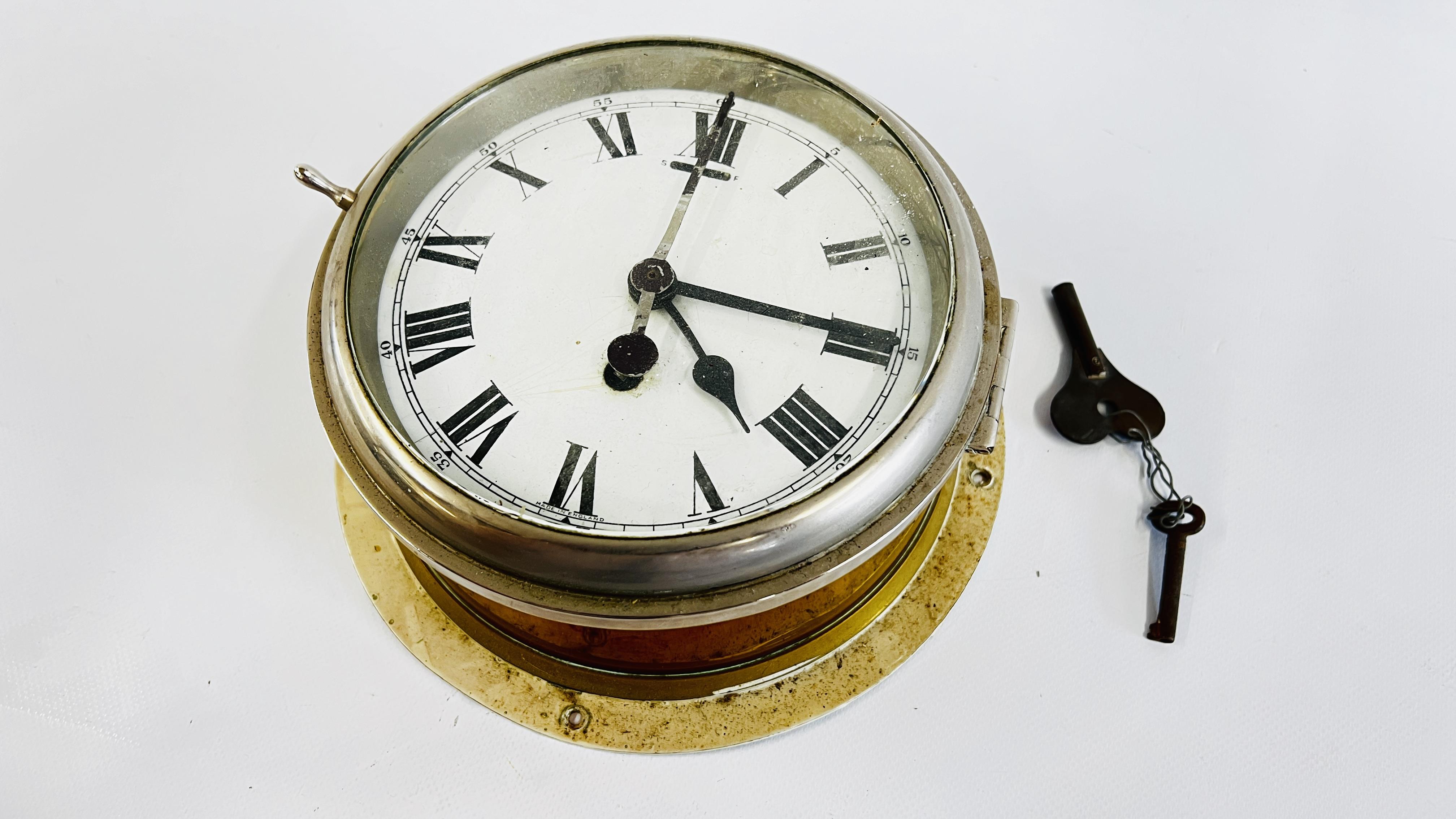 A VINTAGE BRASS CASED SHIPS CLOCK WITH ENAMELLED DIAL.