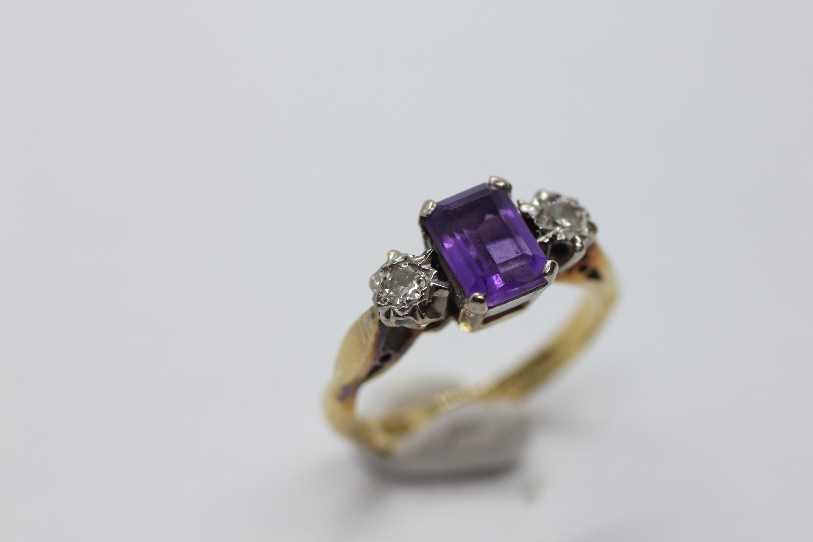 AN 18CT GOLD RING SET WITH A CENTRAL EMERALD CUT AMETHYST AND A DIAMOND EITHER SIDE. - Image 3 of 7