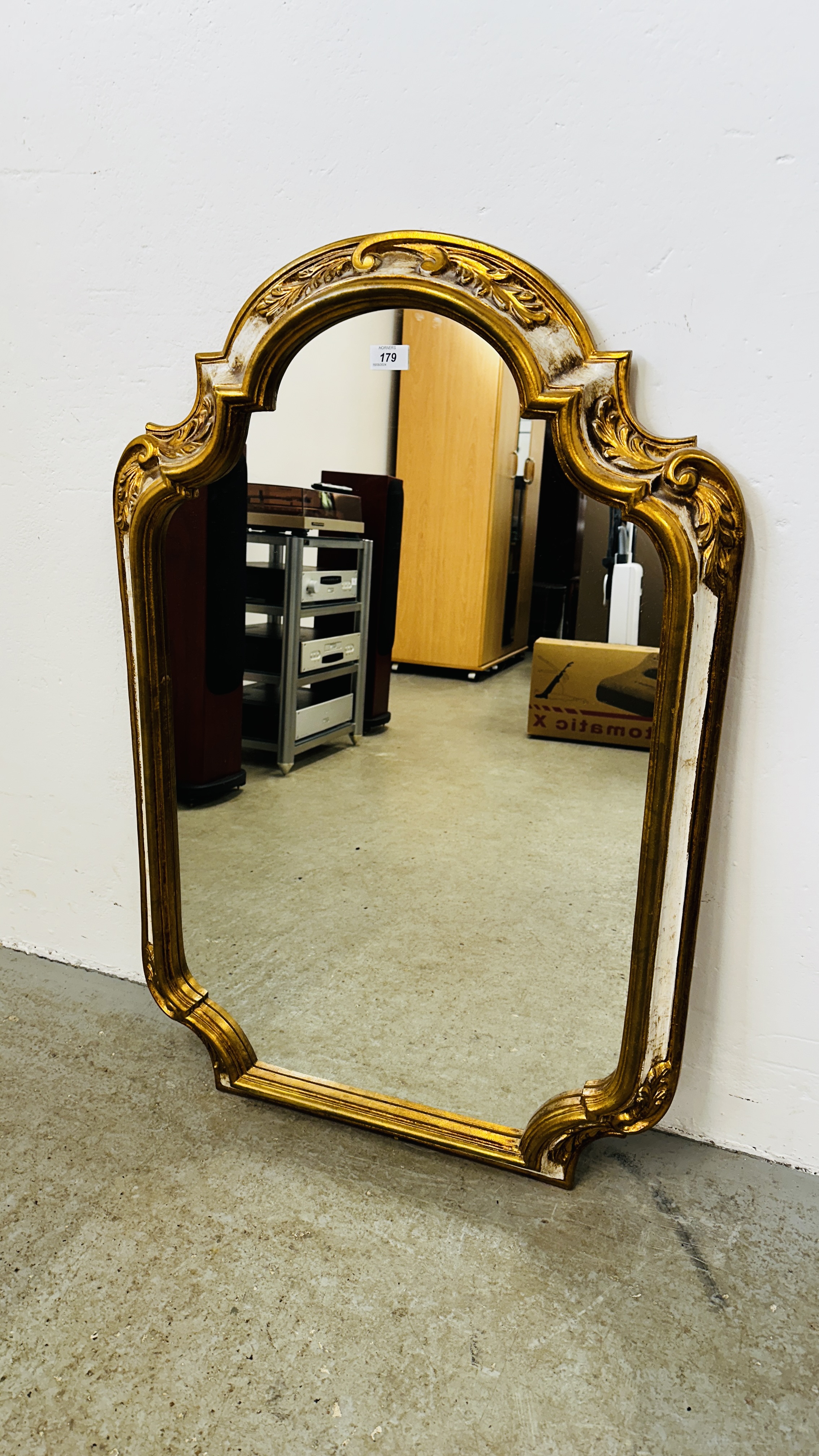 AN ORNATE SHAPED FRAME GILT WALL MIRROR, W 67CM X H 100CM.