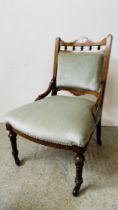 A VICTORIAN MAHOGANY AND INLAID NURSING CHAIR WITH BLUE UPHOLSTERY ON CASTORS.