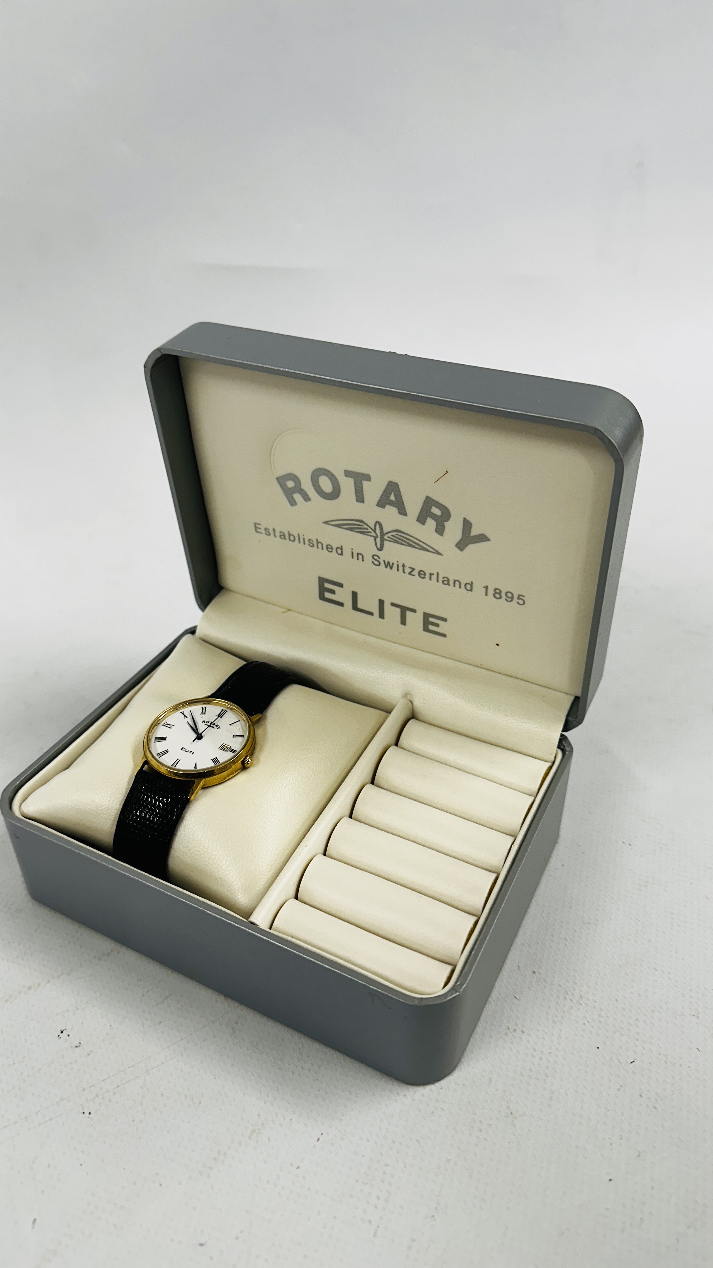 A GENT'S ROTARY ELITE 9CT GOLD CASED WRIST WATCH ON A BLACK LEATHER STRAP (BOXED).