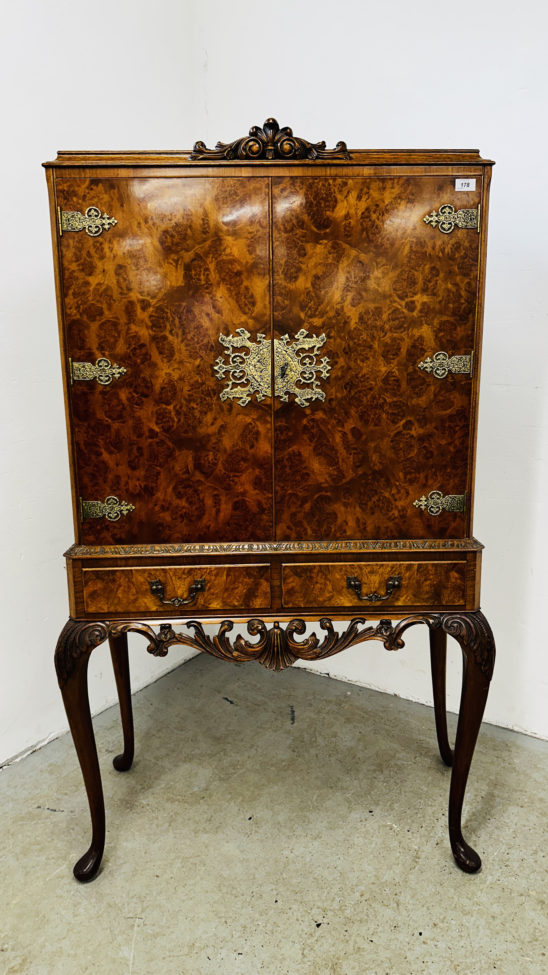 A CONTINENTAL STYLE REPRODUCTION WALNUT FINISH DRINKS CABINET WITH ORNATE BRASS EMBELLISHMENTS,