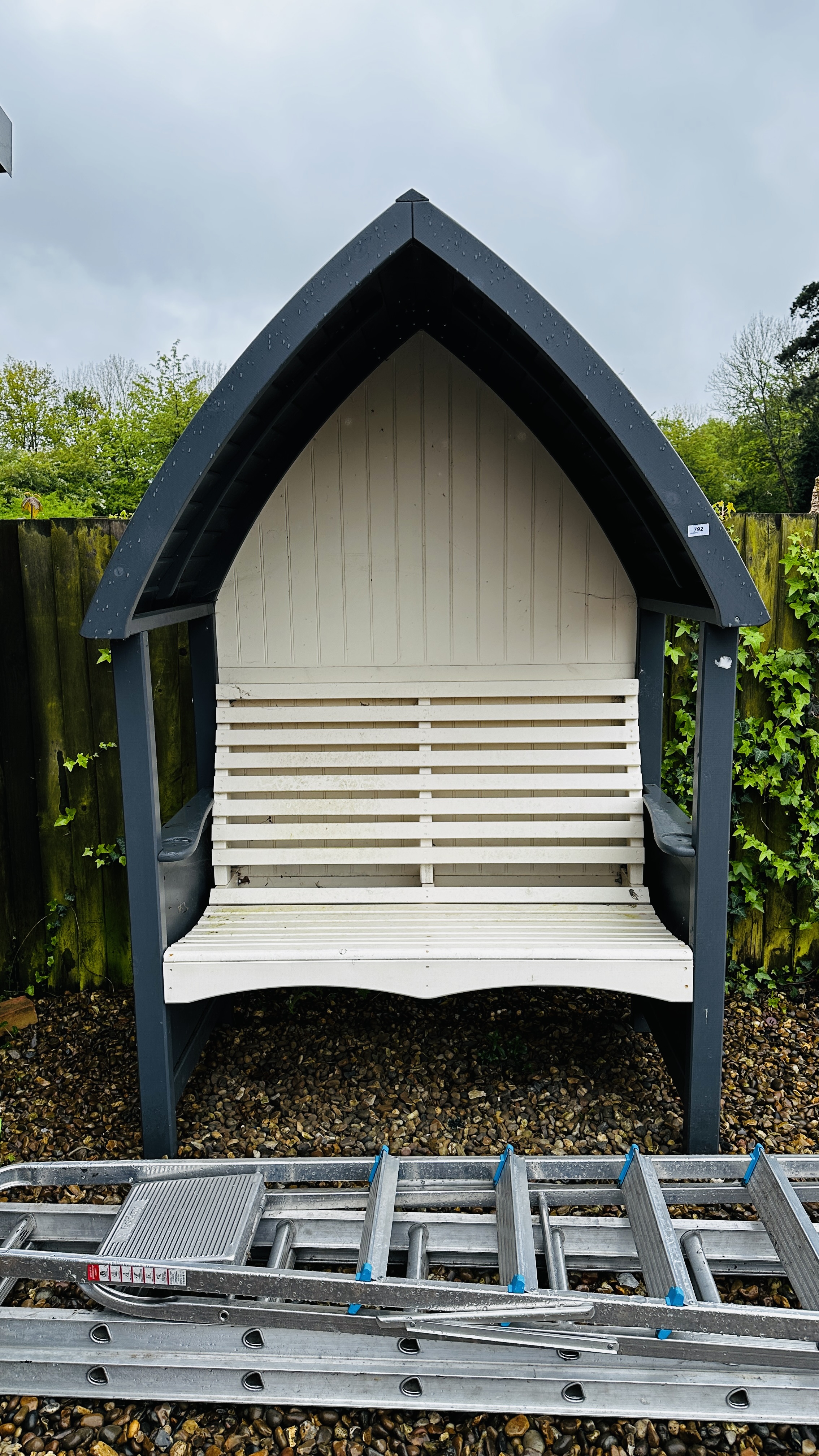 AN ARCHED WOODEN GARDEN ARBOUR SEAT W 140CM.
