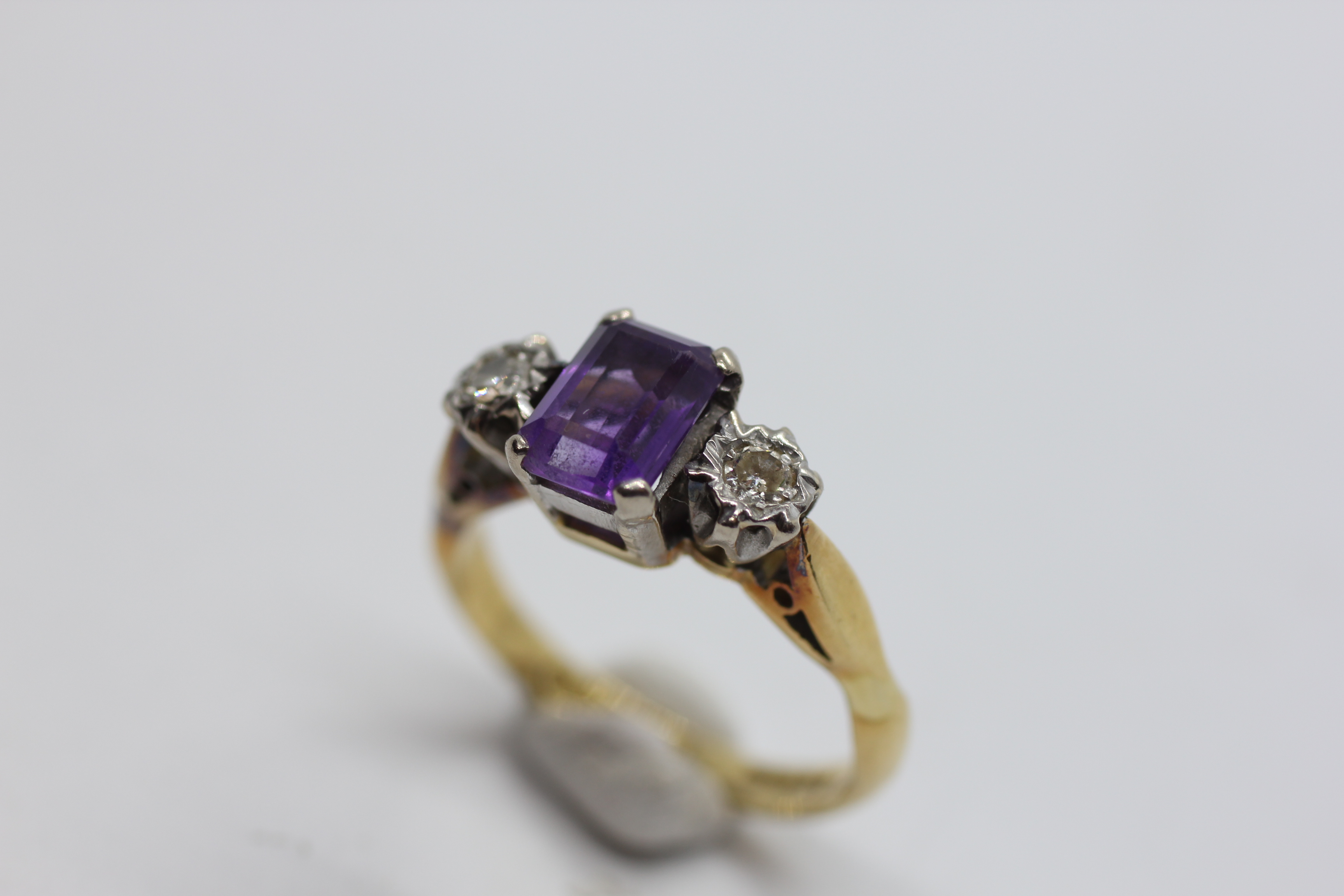 AN 18CT GOLD RING SET WITH A CENTRAL EMERALD CUT AMETHYST AND A DIAMOND EITHER SIDE. - Image 6 of 7