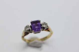 AN 18CT GOLD RING SET WITH A CENTRAL EMERALD CUT AMETHYST AND A DIAMOND EITHER SIDE.