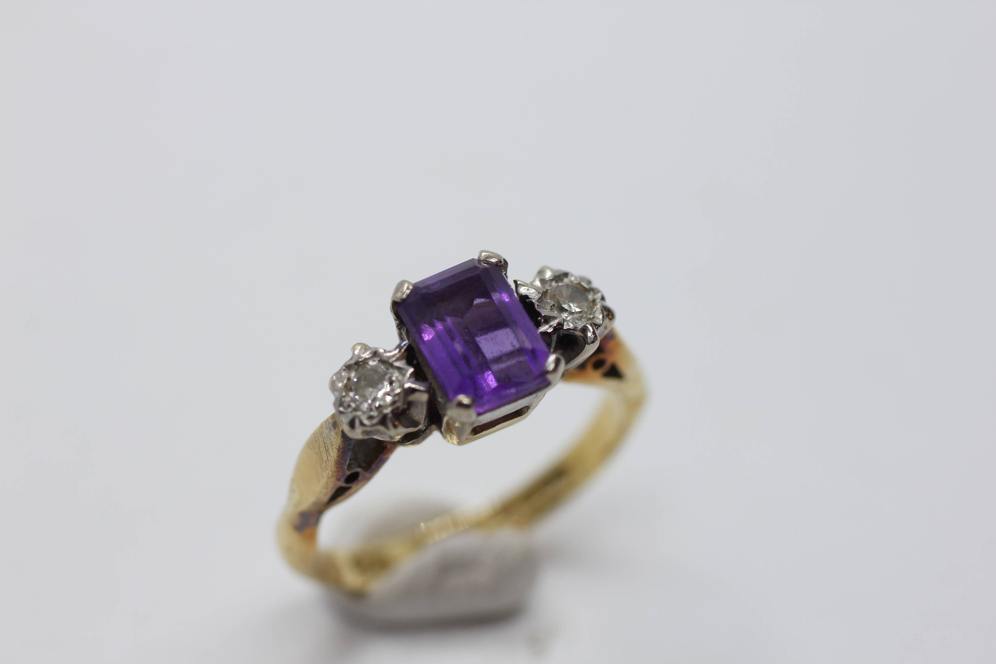 AN 18CT GOLD RING SET WITH A CENTRAL EMERALD CUT AMETHYST AND A DIAMOND EITHER SIDE. - Image 2 of 7