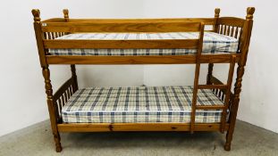 A SOLID HONEY PINE BUNK BED COMPLETE WITH MATTRESSES.