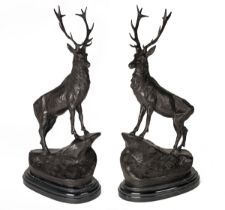 A PAIR OF BRONZE STAGS, each standing on a rocky outcrop and mounted on a black marble oval stand,