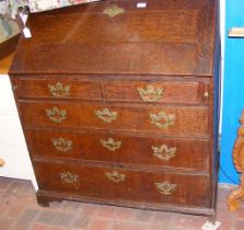 An antique oak bureau with decorative brass mounts