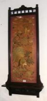 An antique embroidery panel surrounded in mahogany