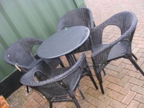 A circular metal garden table with four rattan tub chairs