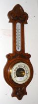 A carved oak banjo shaped wall barometer