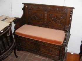A carved oak settle with lift-up seat