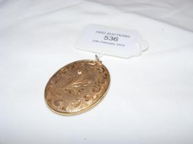 A oval locket with engraved decoration - back and front 9ct with metal core