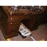 An antique pedestal desk with nine drawers to the