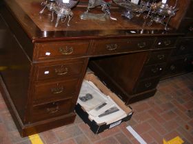 An antique pedestal desk with nine drawers to the