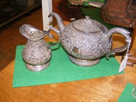 An antique Indian silver teapot and cream jug with