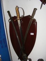 Two bayonets and an antique sword on shaped wooden
